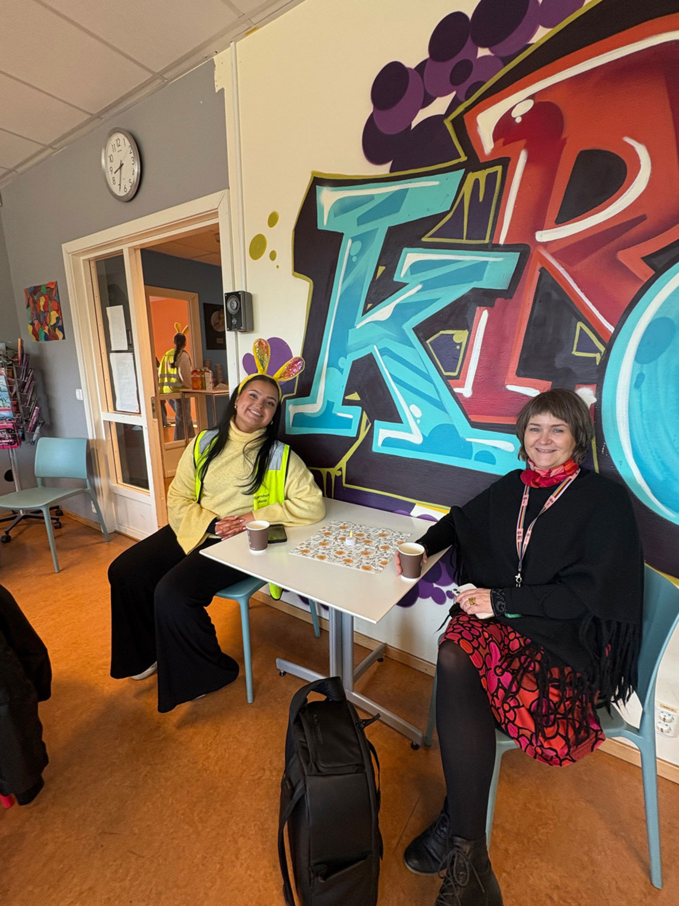 et par personr som sitter ved et bord med en tegneserie på veggen