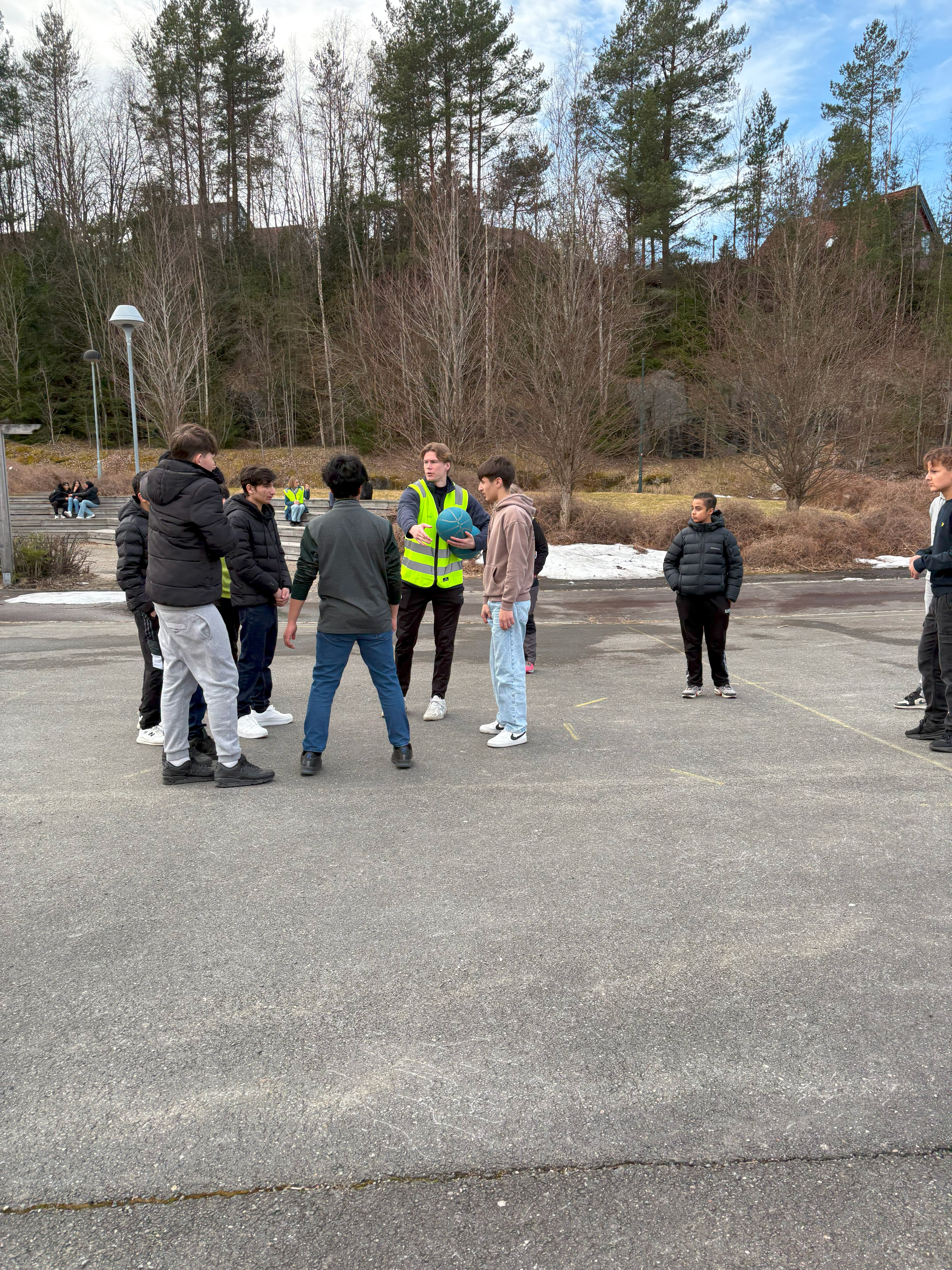 en gruppe mennesker som står på en vei med trær i bakgrunnen